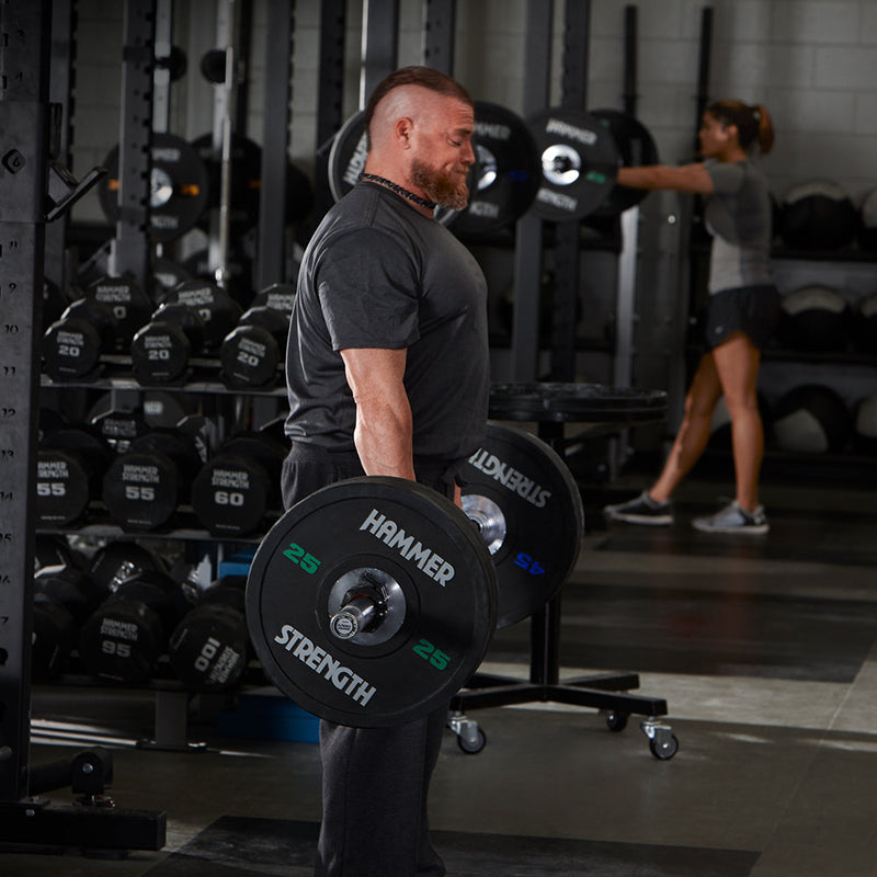 Exerciser deadlifting with Hammer Strength black bumpers