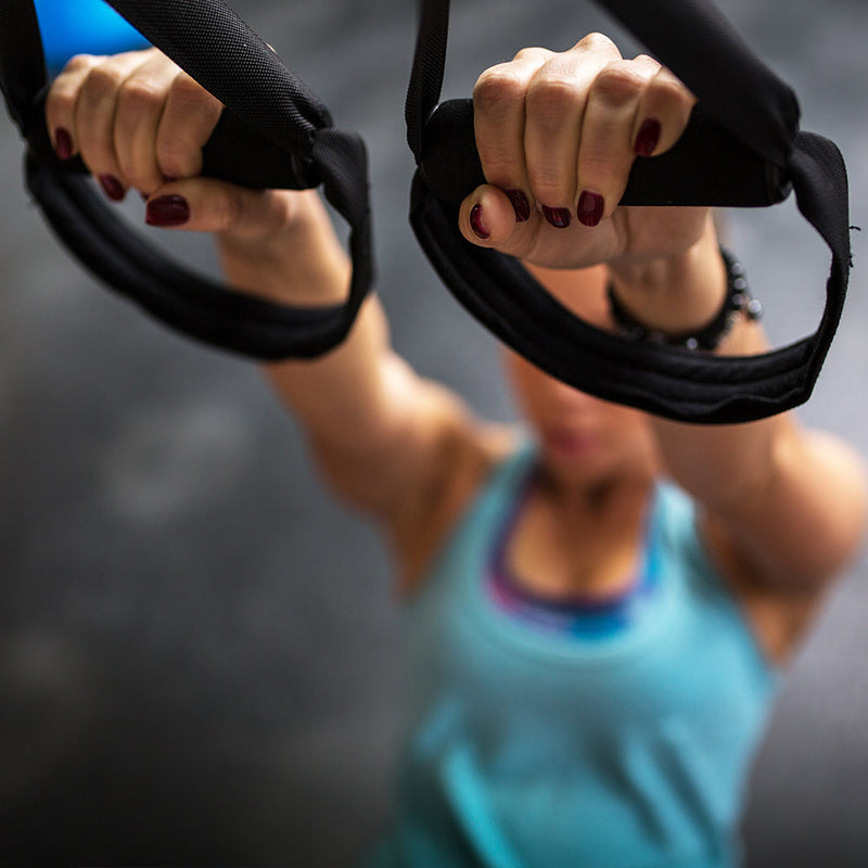 Exerciser gripping TRX strap handles while working out